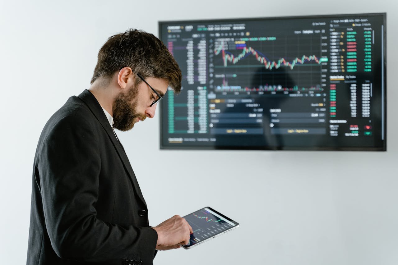 why-choose-us Professional man using tablet in front of cryptocurrency trading screen indoors.